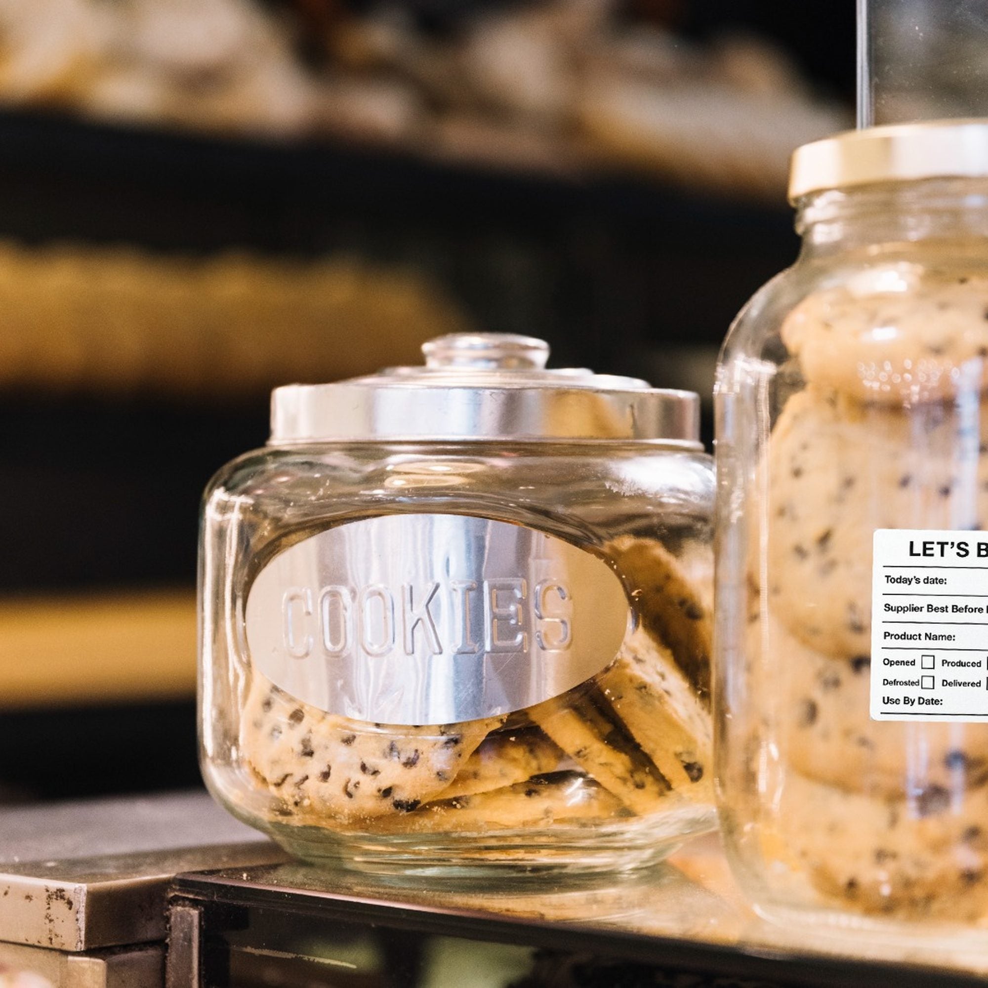 "Waterproof food date label sticker roll"
"Food date labels being applied to container"
"Close-up of easy-peel food date sticker"
"Pack of food date label rolls"